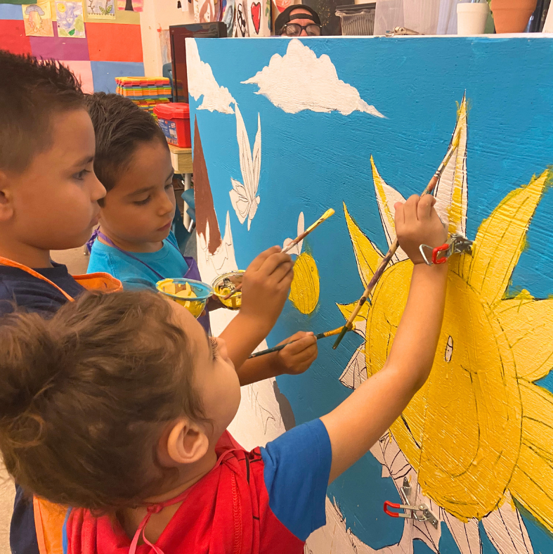 3 youth painting a sky and sun