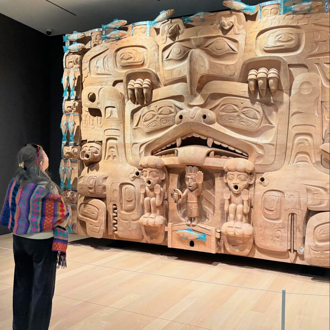 Carmen Guerrero standing in front of largest known wood carving at Audain Museum