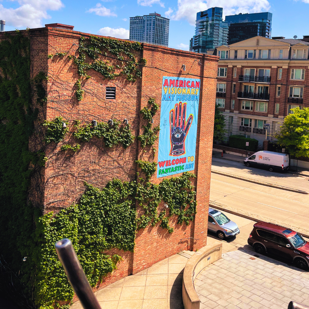 Exterior view of American Visionary Art Museum brick building with painted mural on the side of a multicolored open palm hand